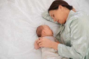 Anne, tatlı küçük bebeğiyle evde, yatağında uyuyor.