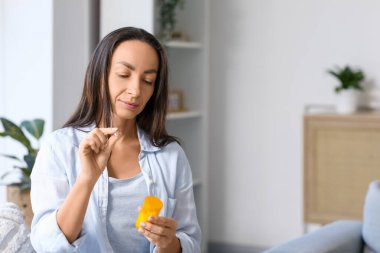 Kadın oturma odasında hap alıyor.