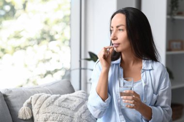 Kadın oturma odasında hap alıyor.