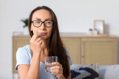 Oturma odasında hap alan güzel bir kadın.