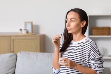 Oturma odasında hap alan güzel bir kadın.