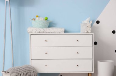Odada bebek aksesuarları olan beyaz çekmeceler.