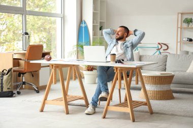 Serbest çalışan evde dizüstü bilgisayarının önünde dinleniyor.