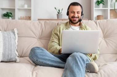 Evde internet işi için bilgisayarı kullanan kulaklıklı bir serbest yazar.