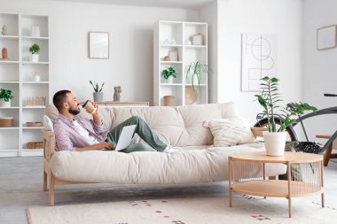 Kanepede yatıp dizüstü bilgisayar kullanan serbest çalışan biri.