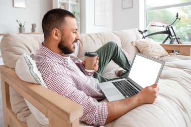 Kanepede yatıp dizüstü bilgisayar kullanan serbest çalışan biri.