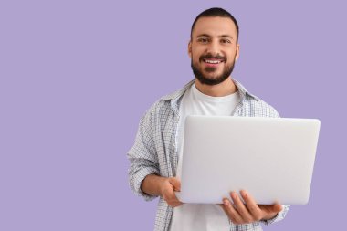 Leylak arkaplanda dizüstü bilgisayarı olan genç bir adam.