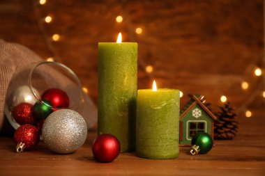 Masada yanan mumlar ve Noel dekoru. Ahşap arka planda ışıklar var.