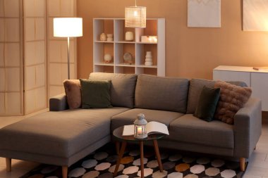 Fenerli kahve masası, rahat kanepe ve oturma odasının içinde parlayan lambalar.