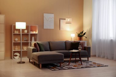 Fenerli kahve masası, rahat kanepe ve oturma odasının içinde parlayan lambalar.