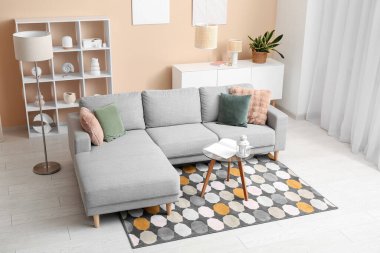 Konforlu kanepe, içinde fener ve kitap olan kahve masası oturma odasının içinde.