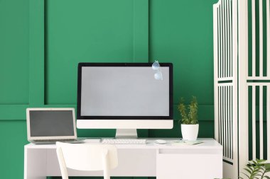 Yeşil duvarın yanında rahat işyeri olan modern odanın içi