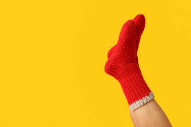 Sarı arka planda kırmızı örgü çoraplı genç bir kadın.