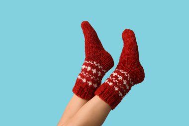 Kırmızı örülmüş çoraplı genç bir kadının bacakları mavi arka planda.