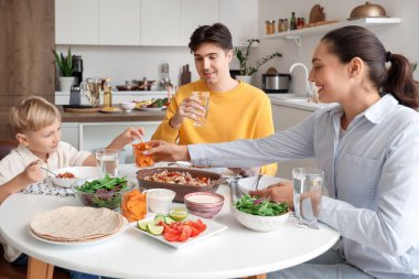 Sevimli küçük çocuk ve ailesi Fajita 'yı mutfakta cipslerle yiyorlar.