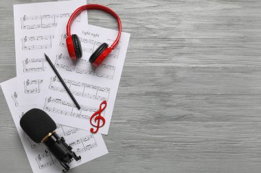 Kulaklıklı müzik kağıtları ve gri ahşap zemin üzerinde mikrofon ve metin için boşluk.