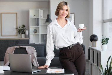 Ofisinde bir fincan kahve ile başarılı bir iş kadını.