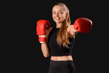 Siyah arka planda boks eldivenli genç bir kadın.