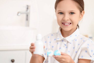 Kontakt lensleri ve bir şişe çözeltisi olan şirin küçük kız, yakın plan.