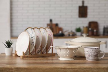 Mutfaktaki ahşap masada farklı mutfak aletleri ve ev bitkileri var.