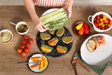 Ahşap masada vejetaryen bruschetalar pişiren bir kadın.