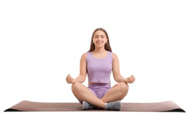 Beyaz arka planda yoga minderinde oturan atletik genç kadın.