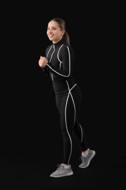 Siyah arka planda takım elbiseli genç bir kadın.