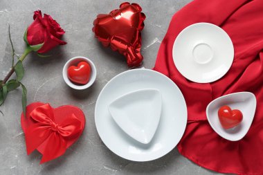 Kırmızı gül, hediye kutusu ve gri arka planda kalp şeklinde hava balonu olan güzel bir masa. Sevgililer Günü kutlaması