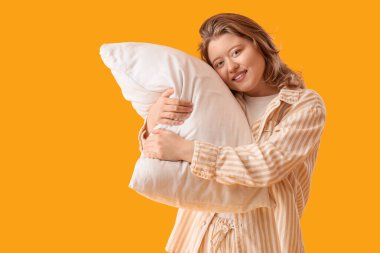 Sarı arka planda yastıklı genç kadın.