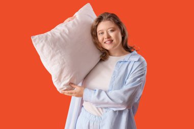 Turuncu arka planda yastığı olan güzel bir kadın.