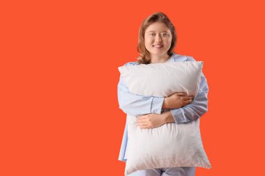 Turuncu arka planda yastığı olan güzel bir kadın.