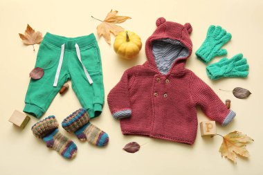 Renkli bebek kıyafetleri, balkabağı ve düşmüş yapraklı kompozisyon