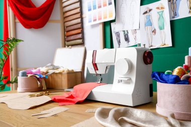 Atölyedeki terzinin masasında malzemeli dikiş makinesi, yakın plan.