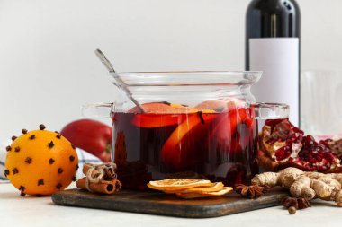 Cam tencere sıcak sıcak şarap ve beyaz arka planda farklı malzemeler.