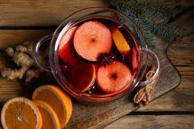 Ahşap arka planda elma ve portakallı sıcak sıcak sıcak şarap demliği.
