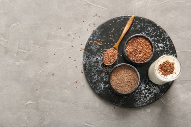 Keten tohumlu bir bardak yoğurt ve arka planda bir kase un.