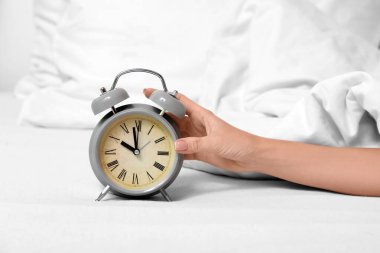 Yatak odasındaki kadın eli çalar saati kapatıyor.