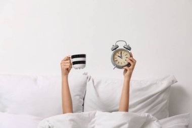 Çalar saati ve kahvesi olan genç bir kadının sabahı.