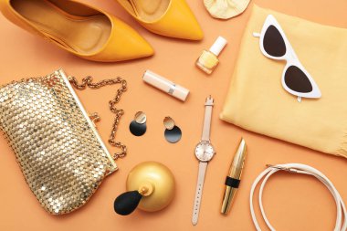 Yüksek topuklu kompozisyon, kozmetik ürünler ve turuncu arka planda aksesuarlar. Yakın çekim.