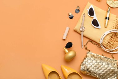 Yüksek topuklu kompozisyon, kozmetik ürünler ve turuncu arka planda aksesuarlar. Üst görünüm