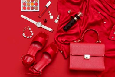 Kırmızı arka planda bluz, ayakkabı, makyaj malzemesi ve aksesuarlı kompozisyon. Yakın çekim.