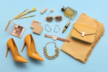 Yüksek topuklu kompozisyon, kozmetik ürünler ve mavi arka planda aksesuarlar. Üst görünüm