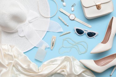 Mavi arka planda güneş gözlüğü, kozmetik ve aksesuarlı kompozisyon. Yakın çekim