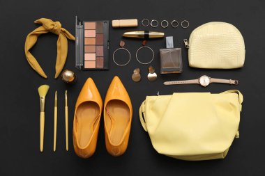 Kozmetik ürünleri, aksesuarlar, saç bandı ve siyah arka planda ayakkabılar. Üst görünüm