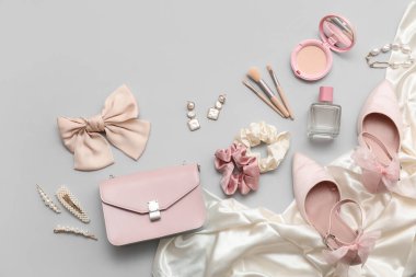 Kozmetik ürünleri, aksesuarlar, gri arka planda fiyonk ve çanta. Yakın çekim.