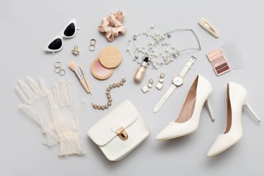 Kozmetik ürünleri, aksesuarlar, yüksek topuklu ayakkabılar ve gri arka planda eldivenler. Üst görünüm