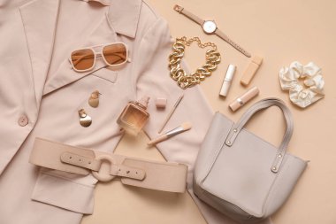 Bej arka planda kozmetik, aksesuar, ceket ve kemer kompozisyonu. Yakın çekim.