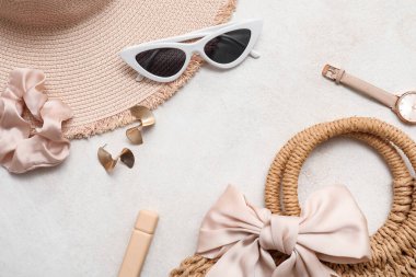 Kozmetik ürünleri, aksesuarlar, güneş gözlüğü ve gri arka planda şapka. Yakın çekim.