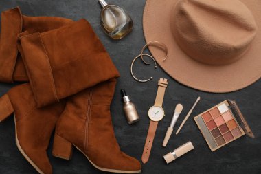 Siyah arka planda kozmetik, aksesuar, bot ve kol saati olan kompozisyon. Yakın çekim.