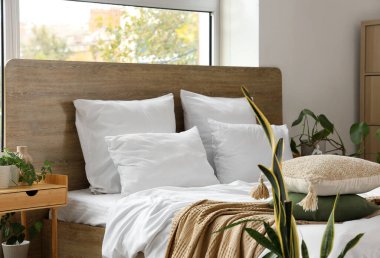 Rahat yataklı, komodinli ve çiçekli, aydınlık yatak odasının içi.